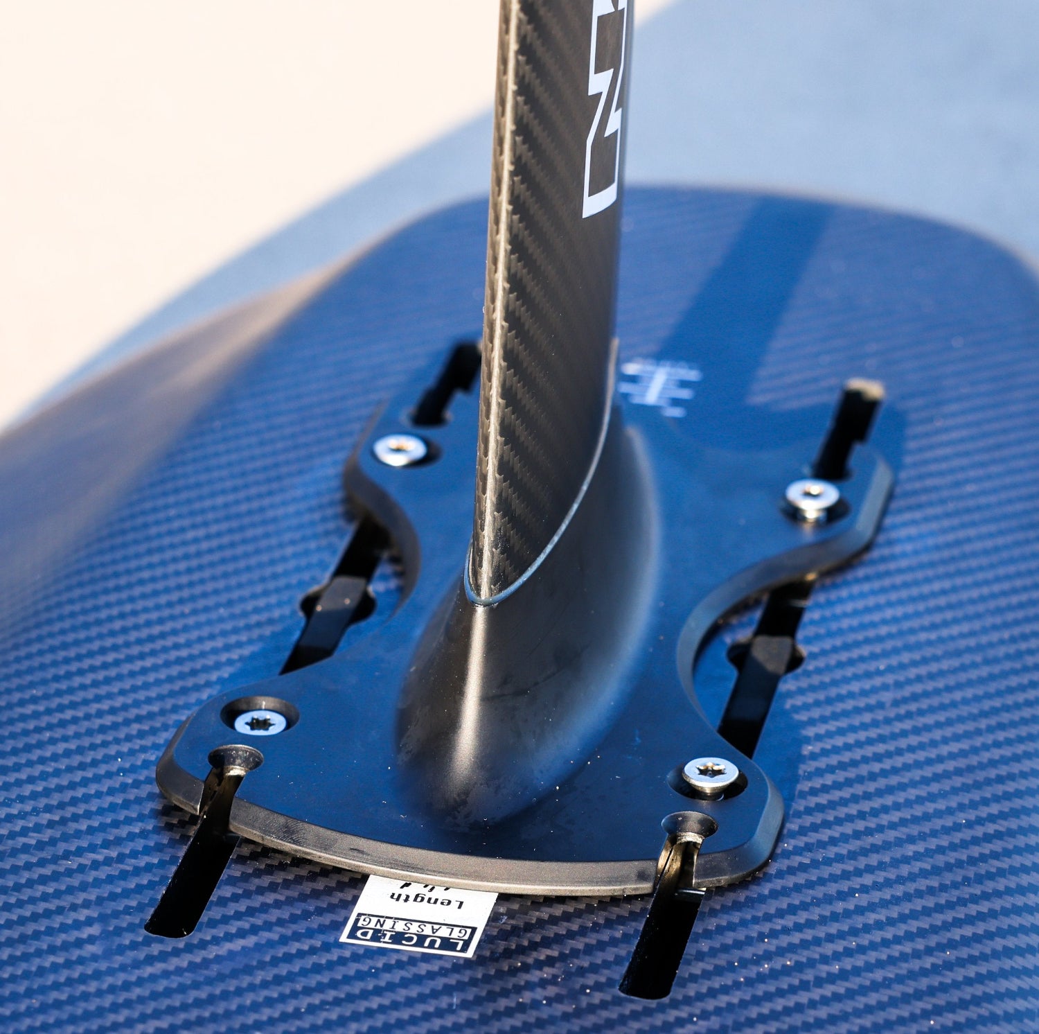 Detail shot of a NoLimitz hydrofoil mast mounted on a black Amos Shapes carbon foilboard