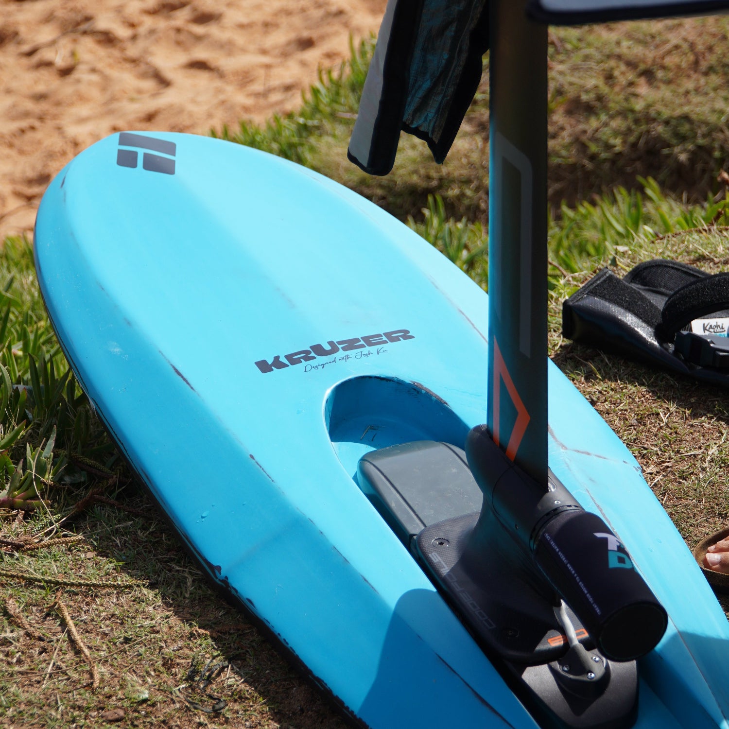 Kruzer RTS Foil Drive board a foilboard by Amos Shapes lying on the beach equipped with Foil Drive assist max kit