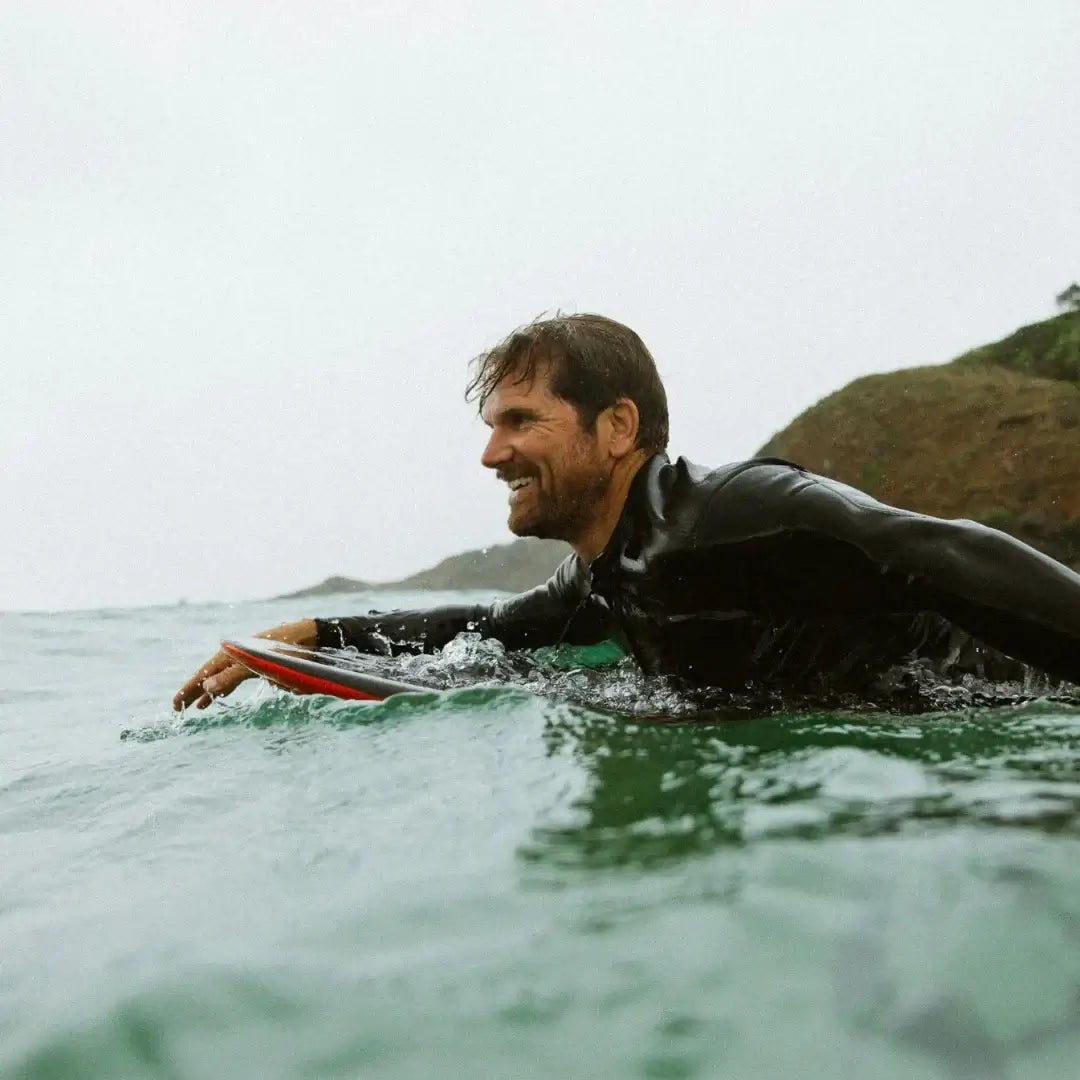 Amos Shapes KrUzer V2 rider on wave surfing in wetsuit with surf foilboard.