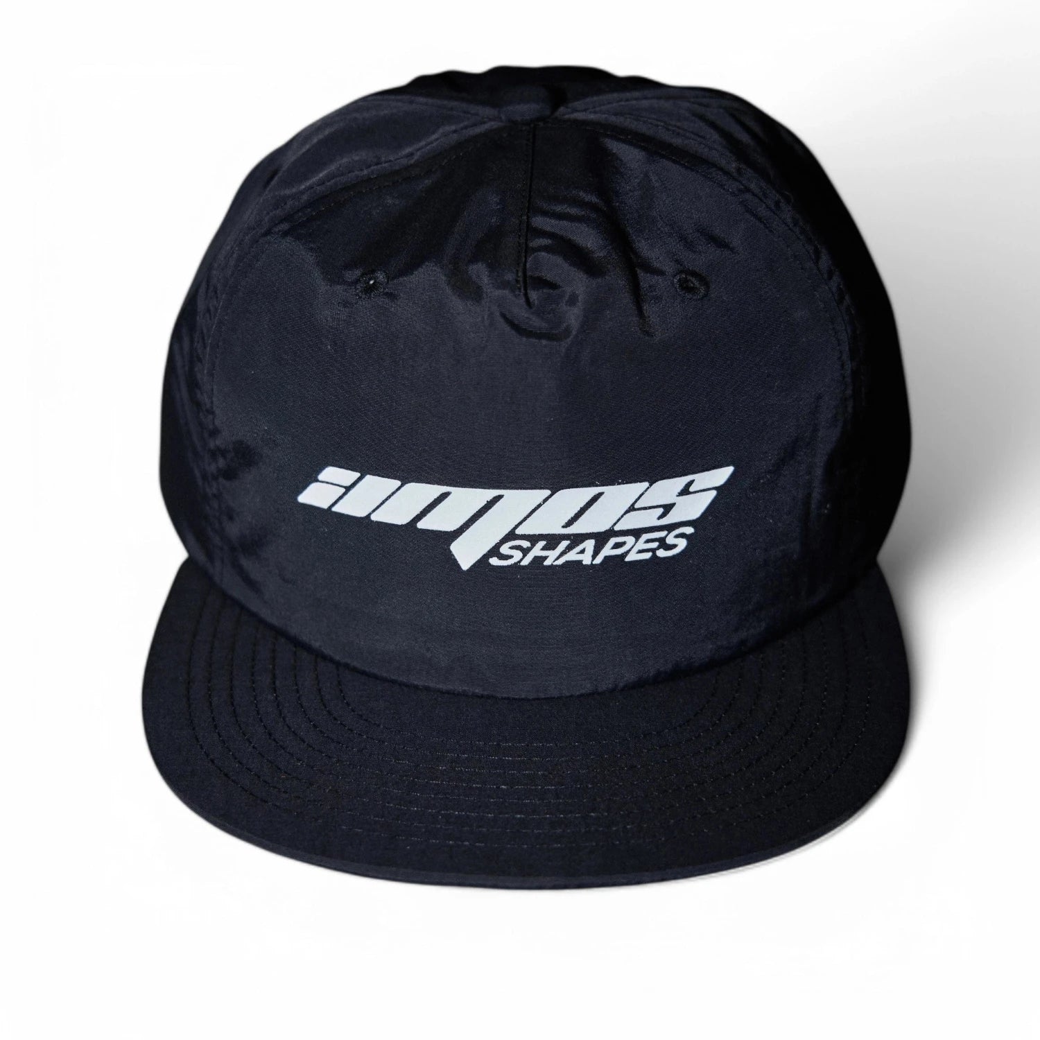 Front view of a black Amos Shapes surf hat with a white logo