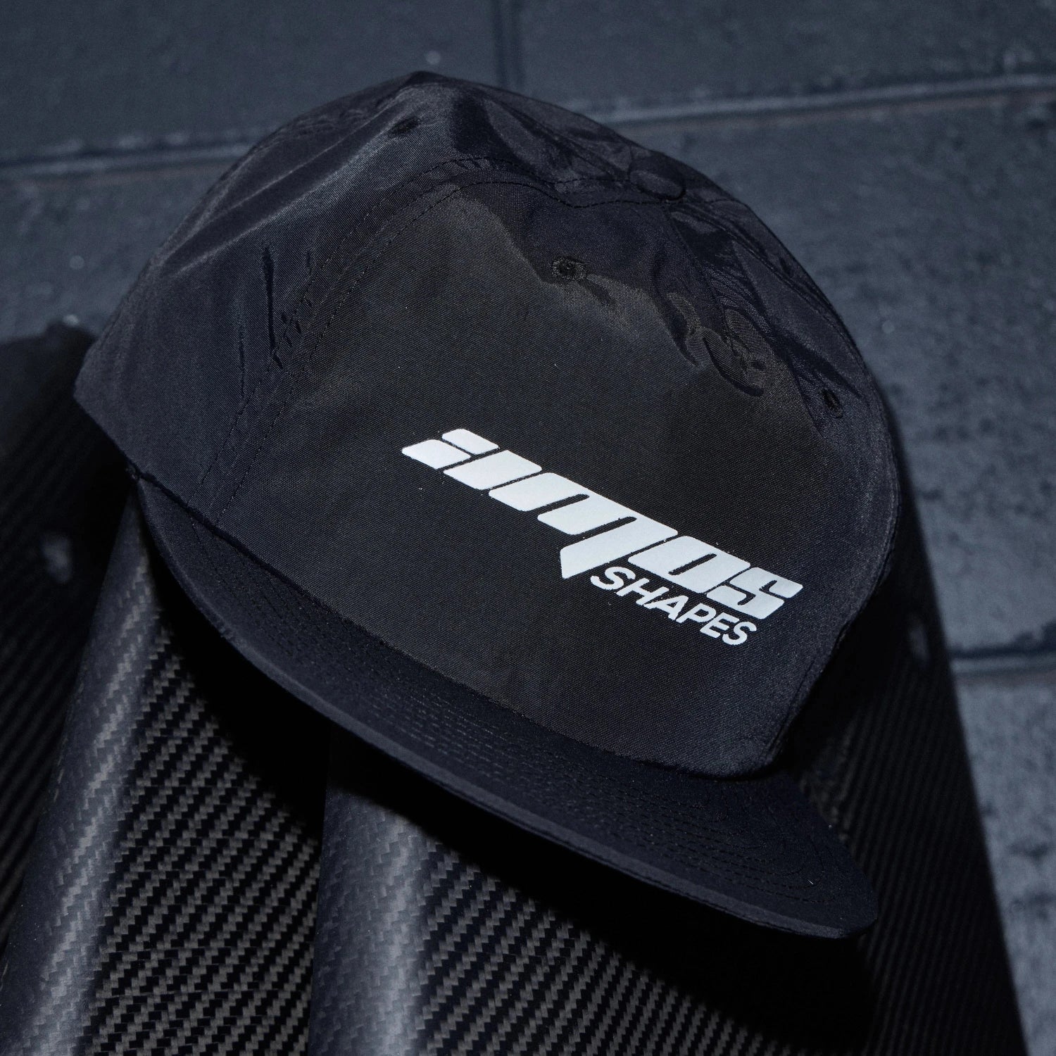 Black surf cap with Amos Shapes logo in white on the front