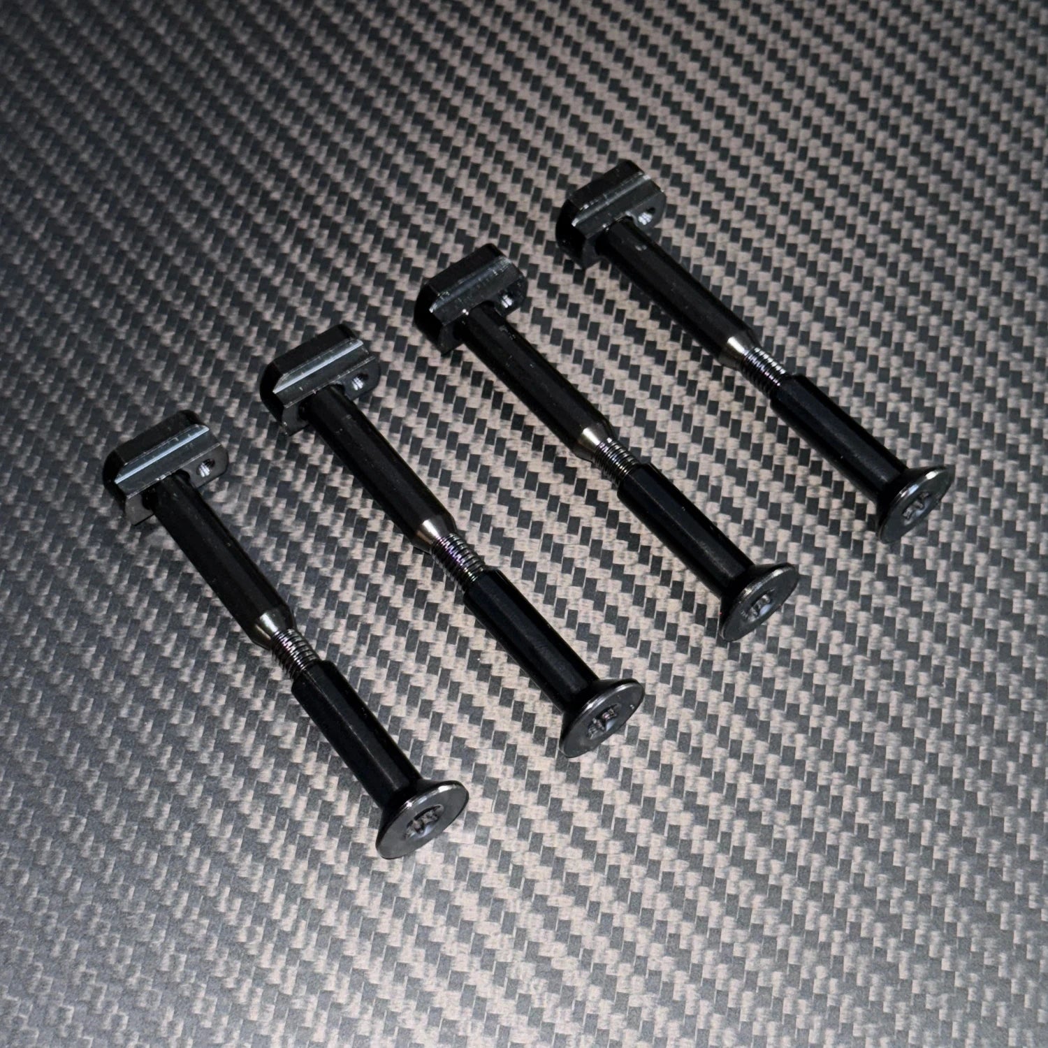 Close up shot of four Foil Drive split bolts on a black carbon foilboard background