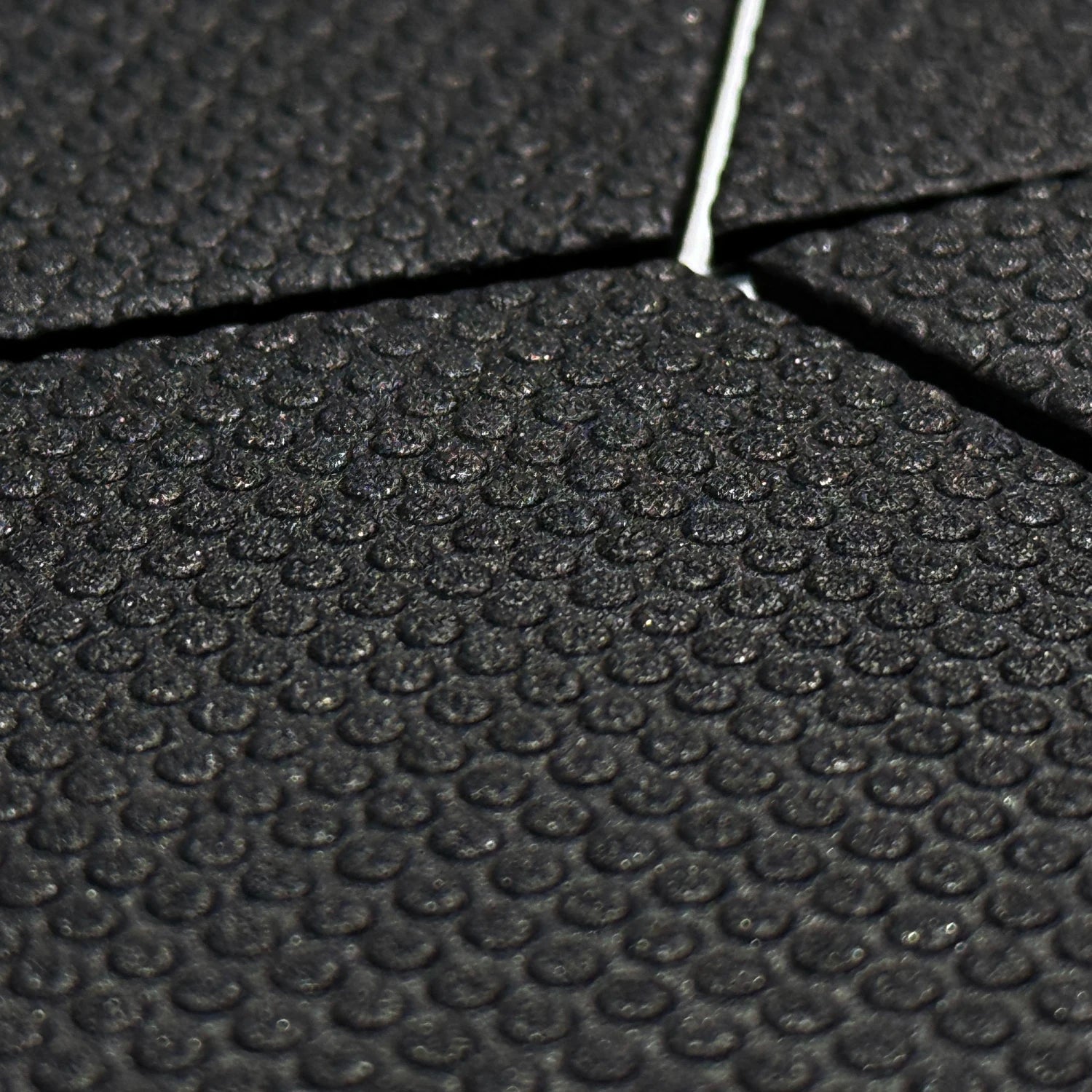 Detail shot of a black six-piece Foil Tec foilboard traction pad showing its dotted texture