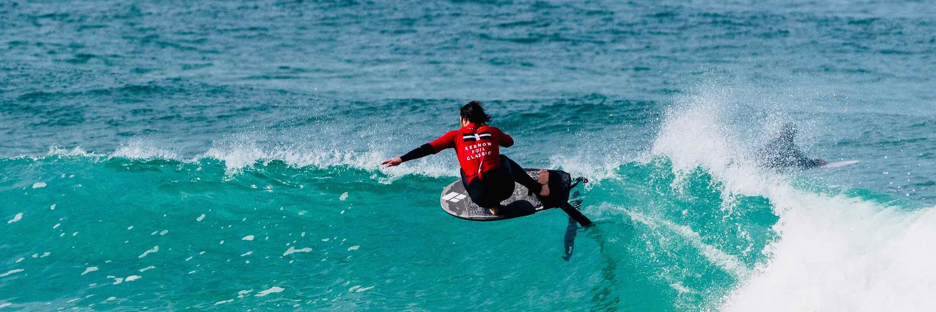A man riding a surf foilboard on an Amos Shapes Foilboard and Lift Foils hydrofoil with his arms out wide 