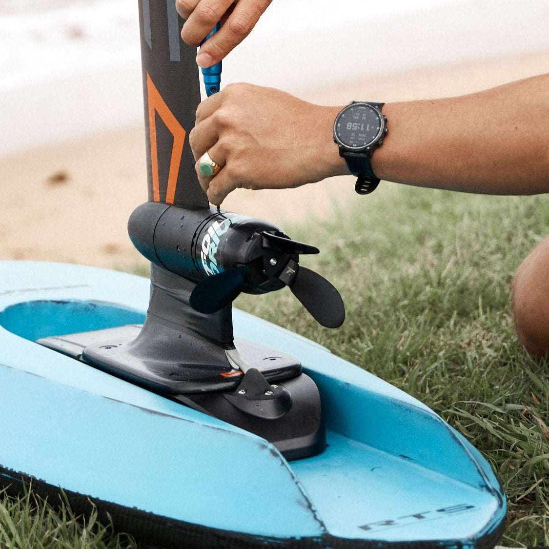 Person attaching a propeller for Foil Drive to a Kruzer RTS foil board from Amos Shapes on the grass 