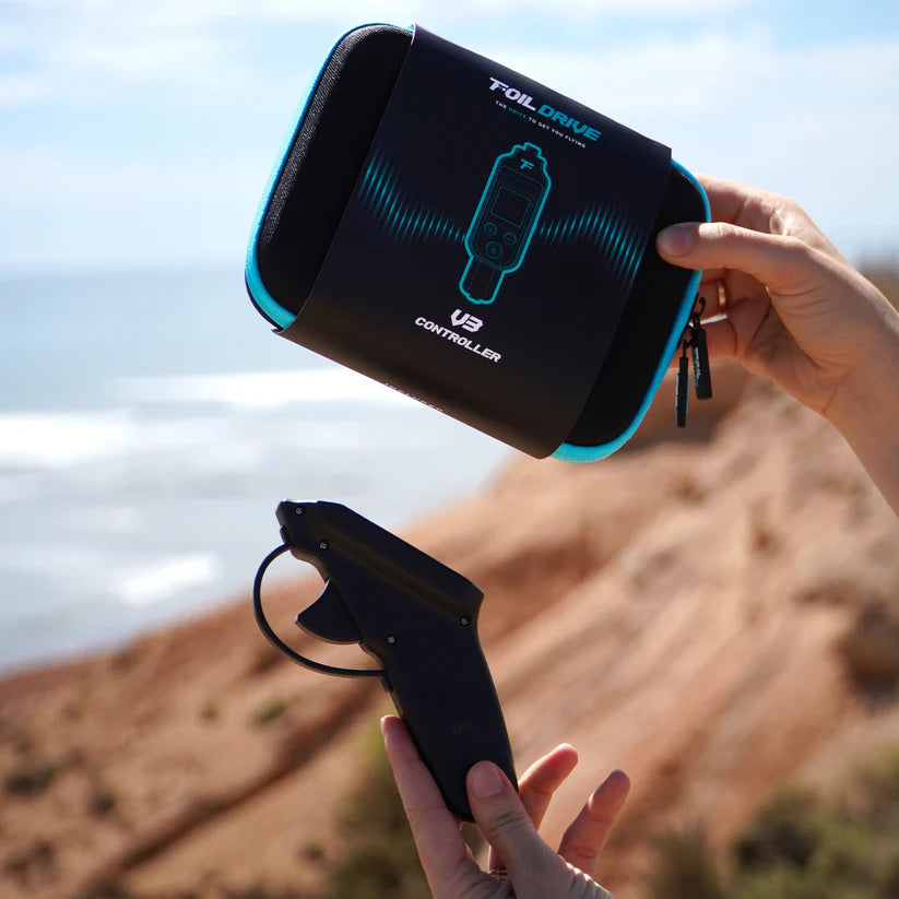 Foil Drive V3 Controller and branded carry case held in hands with the beach and ocean in the background.