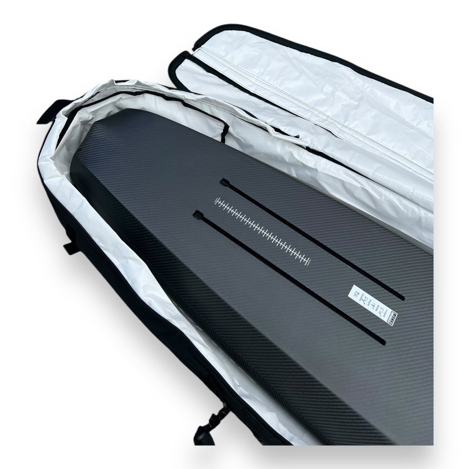 Bottom view of a black carbon foilboard showing its tracks inside a black Foil Tec foilboard travel bag with white inside lining